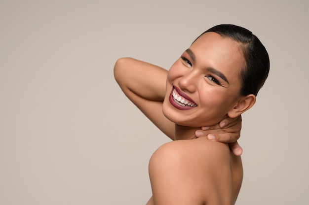 Portrait of beautiful asian woman touches neck with big smiles