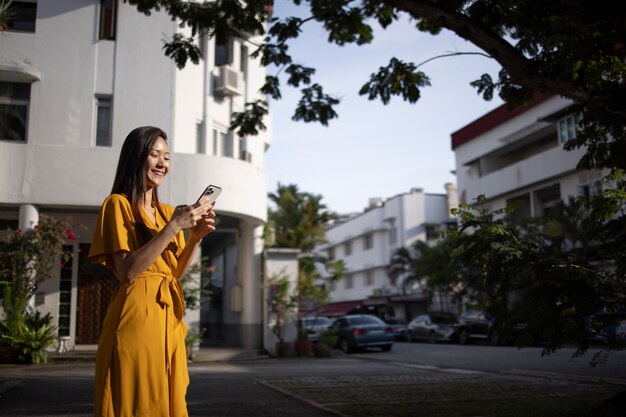 Портрет красивой азиатской женщины, использующей смартфон на открытом воздухе в городе