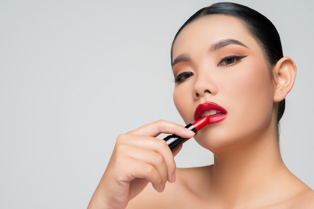 Portrait of Beautiful Asian woman with lipstick in hand