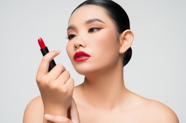 Portrait of Beautiful Asian woman with lipstick in hand