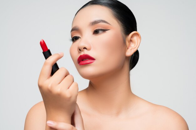 립스틱을 손에 들고 있는 아름다운 아시아 여성의 초상화