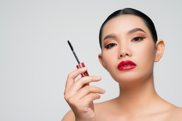 Free Photo portrait of beautiful asian woman with mascara in hand