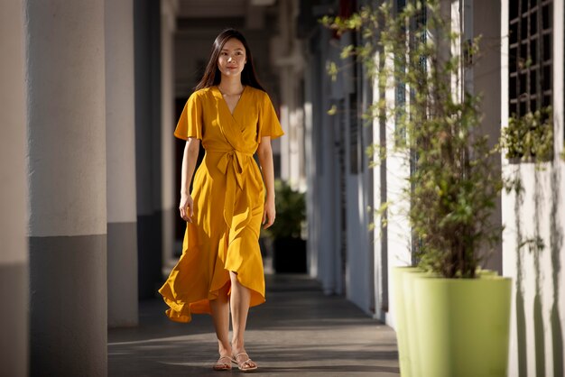 Портрет красивой азиатской женщины в желтом платье, позирующей на открытом воздухе в городе