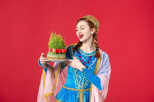 Portrait of beautiful azeri woman in traditional dress with semeni on red