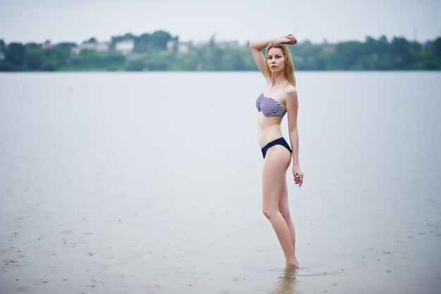 Portrait of a beautiful bikini model standing and posing in the water