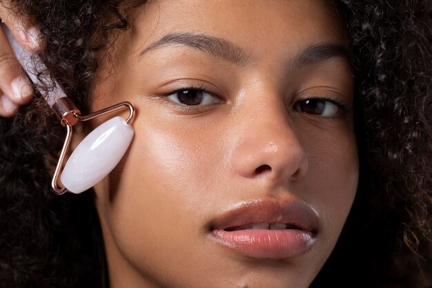 Portrait of beautiful black woman using a jade roller on her face