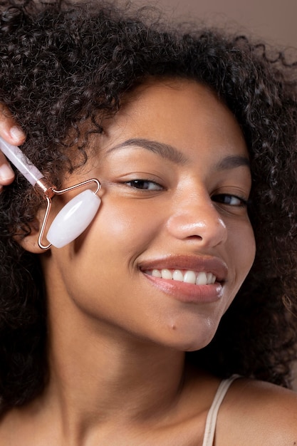 Free photo portrait of beautiful black woman using a jade roller on her face