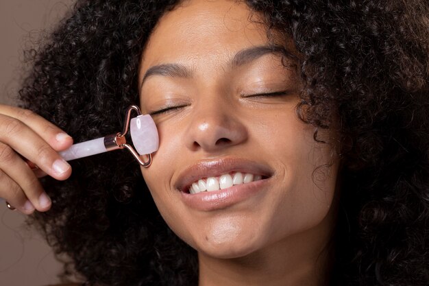 Portrait of beautiful black woman using a jade roller on her face