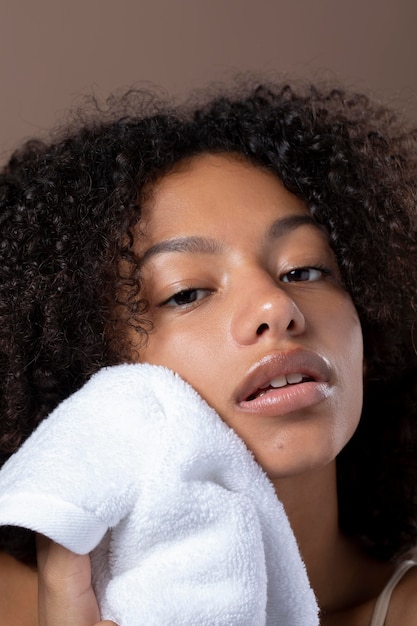 Free photo portrait of beautiful black woman using a white towel on her face