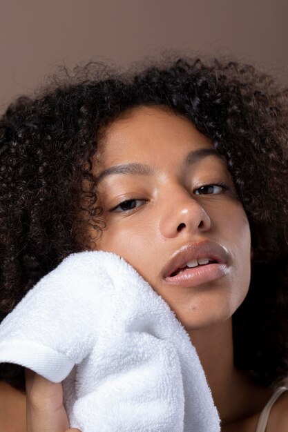 Portrait of beautiful black woman using a white towel on her face