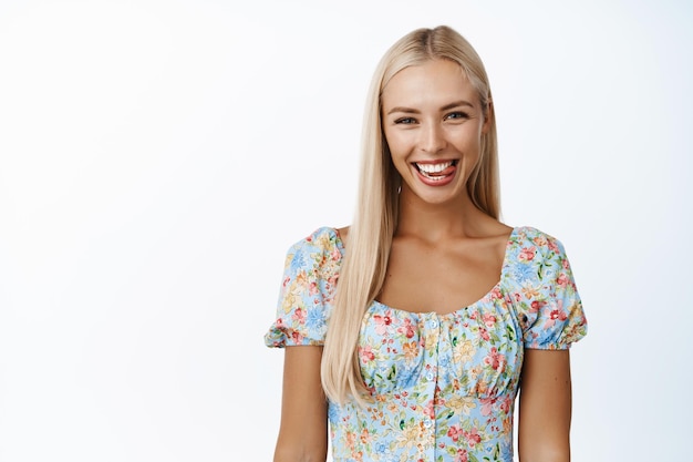 Портрет красивой блондинки кавказской женщины, улыбающейся и счастливой перед камерой, позирующей в летнем платье на белом фоне