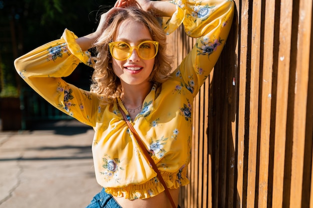 Free photo portrait of beautiful blond stylish smiling woman in yellow blouse wearing sunglasses