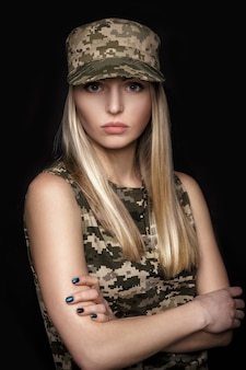 Portrait of a beautiful blond woman soldiers in military attire on black background