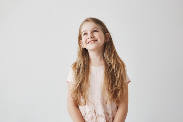 Foto gratuita ritratto di bella bambina bionda con gli occhi azzurri, essendo in gita scolastica nello zoo, guardando a lato giraffa con espressione faccia felice.