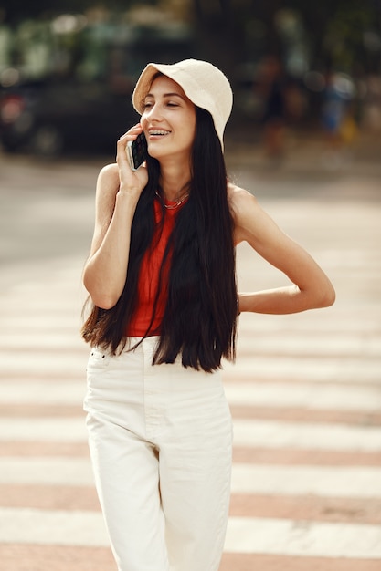 Портрет красивой брюнетки. Модель в летнем городе. Женщина ходит с мобильным телефоном.