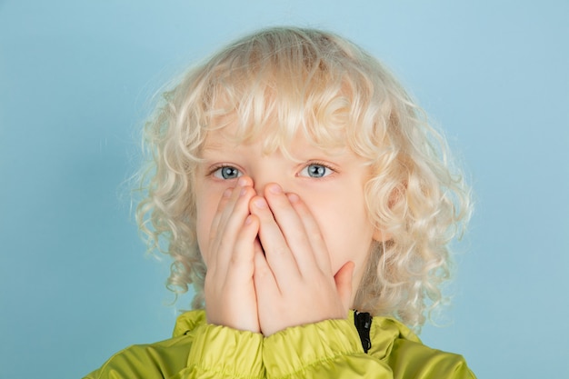 Portrait of beautiful caucasian little boy isolated on blue studio wall