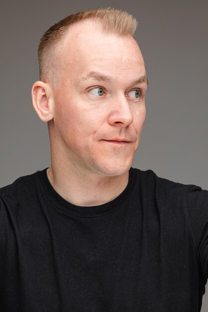 Portrait of beautiful caucasian male in black t-shirt looks at something interesting 