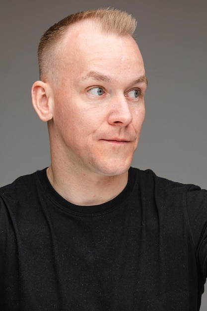 Portrait of beautiful caucasian male in black t-shirt looks at something interesting 