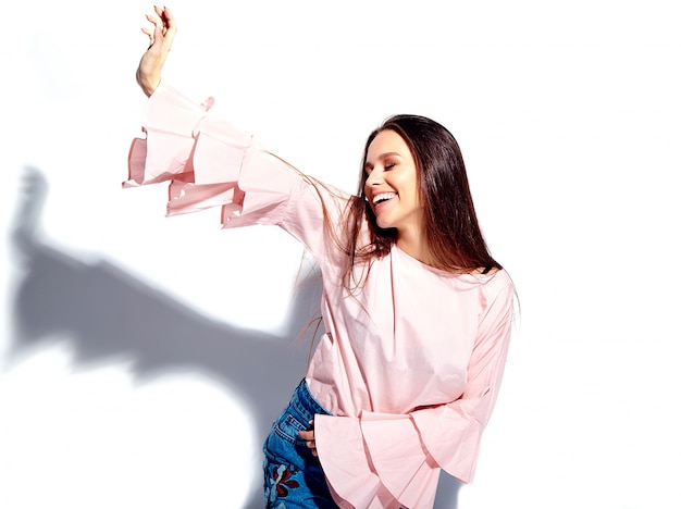 Portrait of beautiful caucasian smiling brunette woman model in bright pink blouse and summer stylish blue jeans with flowers print