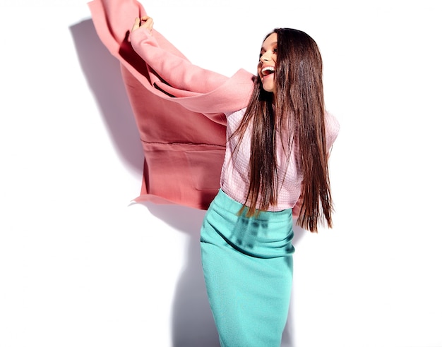 Портрет красивой кавказской улыбающейся брюнетки модели в ярко-розовом пальто и летней стильной синей юбке