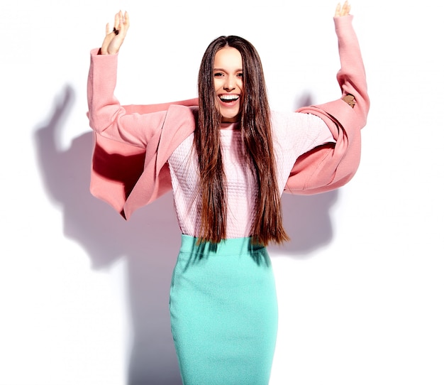 Portrait of beautiful caucasian smiling brunette woman model in bright pink overcoat and summer stylish blue skirt 