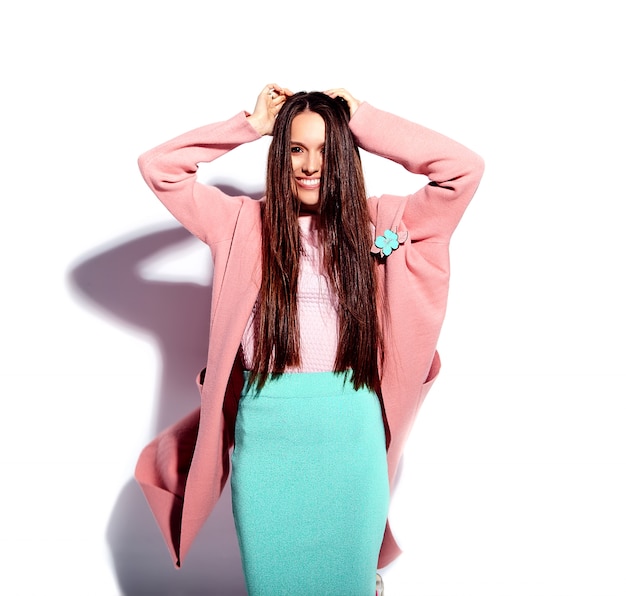 Portrait of beautiful caucasian smiling brunette woman model in bright pink overcoat and summer stylish blue skirt