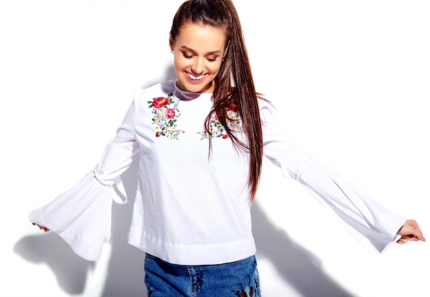 Portrait of beautiful caucasian smiling brunette woman model in white blouse and summer stylish blue jeans with flowers