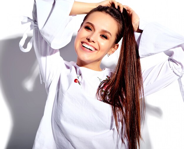 Portrait of beautiful caucasian smiling brunette woman model in white blouse and summer stylish blue jeans with flowers