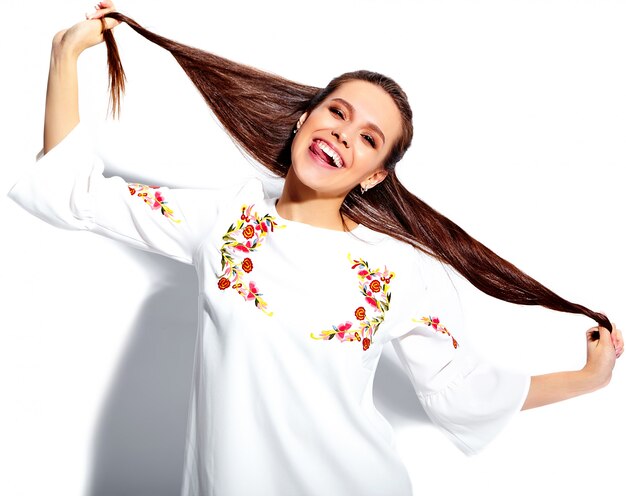 Портрет красивой кавказской усмехаясь модели женщины брюнет в платье белого лета стильном изолированном на белой предпосылке. Скручивать волосы