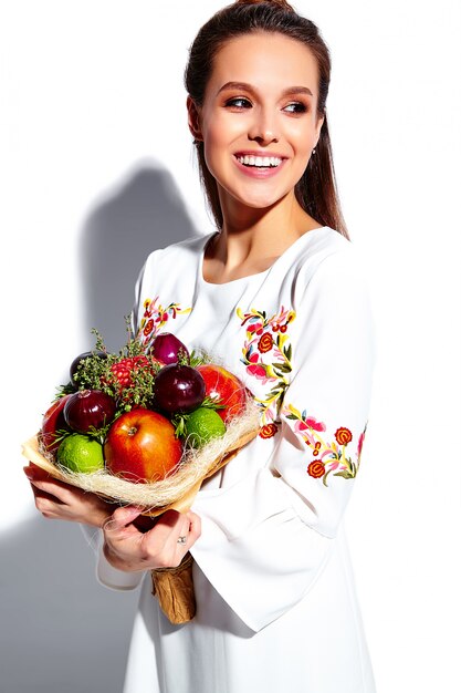 Portrait of beautiful caucasian smiling brunette woman model in white summer stylish dress with unusual creative bouquet of flowers