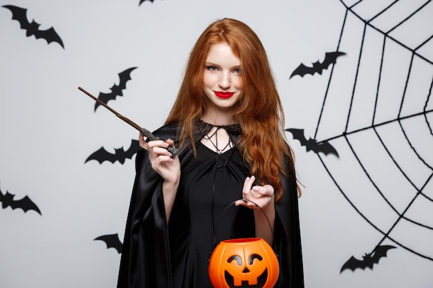 Portrait of beautiful caucasian witch holding orange pumpkin for celebrating halloween.