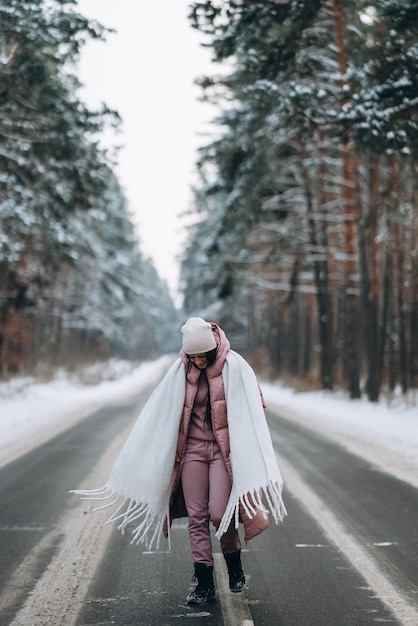 Portrait of a beautiful caucasian woman on a road in snowy forest