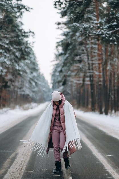 Portrait of a beautiful caucasian woman on a road in snowy forest