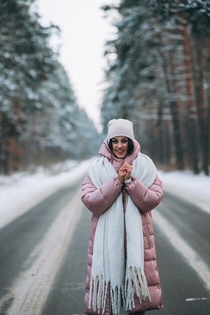 Portrait of a beautiful caucasian woman on a road through snowy forest