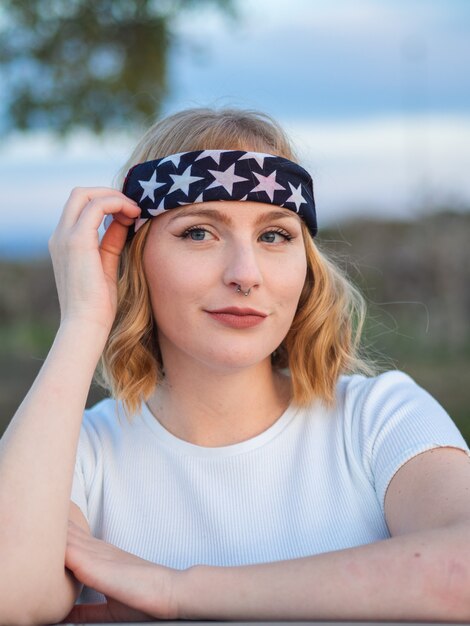 Portrait of a beautiful Caucasian woman with a nose ring and a trendy bandana at a park