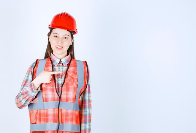 Portrait of beautiful construction worker pointing on white background. 