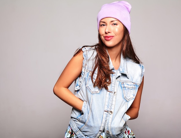 Portrait of beautiful cute brunette woman model in casual summer jeans clothes with no makeup in purple beanie isolated on gray