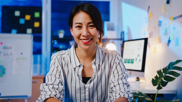 Portrait of beautiful executive businesswoman smart casual wear looking at camera and smiling, happy in modern office workplace night.