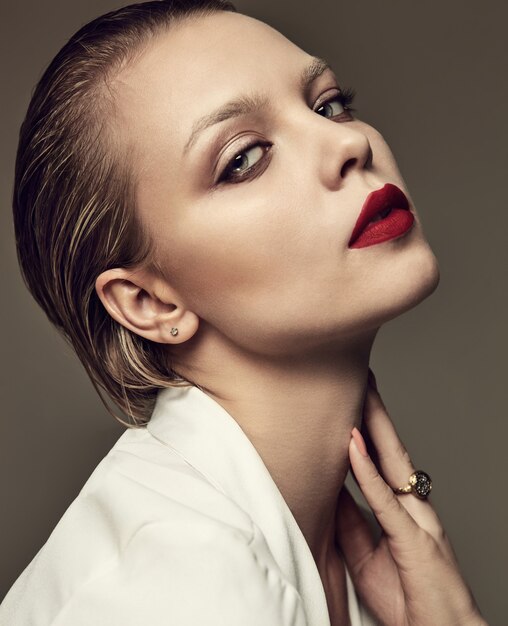 Portrait of beautiful fashion stylish brunette woman model with evening makeup and red lips in white jacket