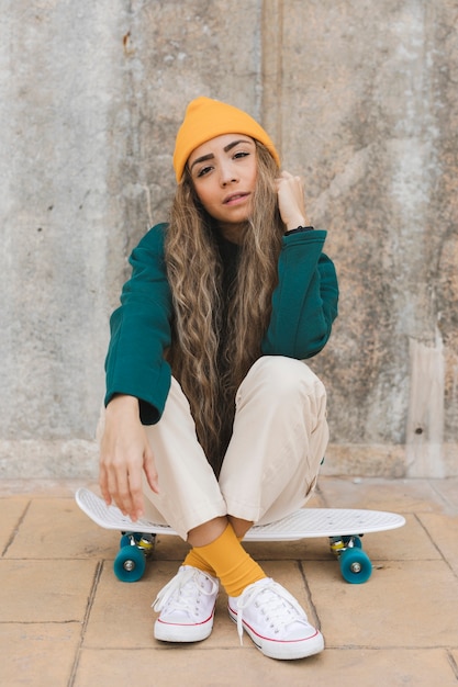 Portrait beautiful female sitting on skateboard