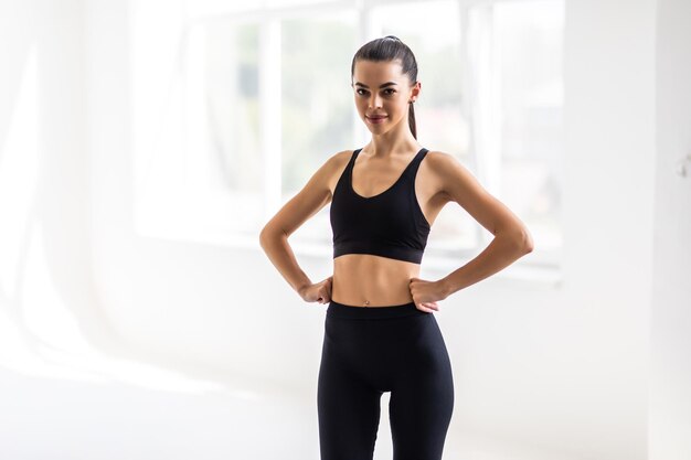 Portrait of beautiful fitness woman smiling and looking at camera isolated on grey background Young woman in sportswear relaxing after training at gym