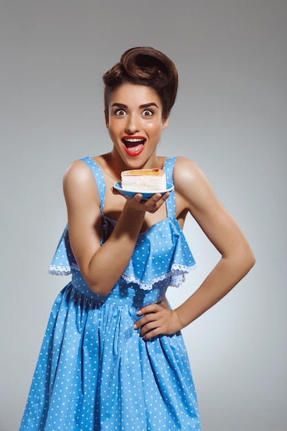 Free photo portrait of beautiful funny pin-up woman holding cake in hands