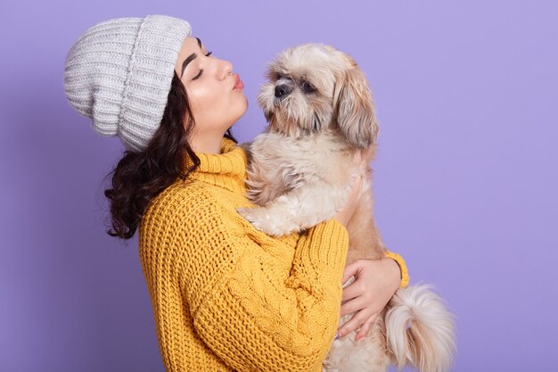 Portrait of beautiful girl keeping pretty Pekingese and wants kissing him