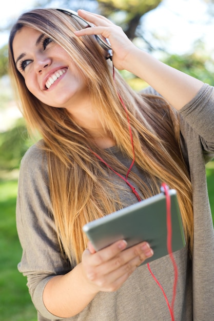 Ritratto di bella ragazza ascoltando musica con tabella digitale