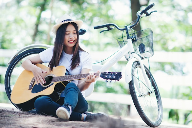 자연에서 자전거와 기타를 연주하는 아름 다운 여자의 초상화