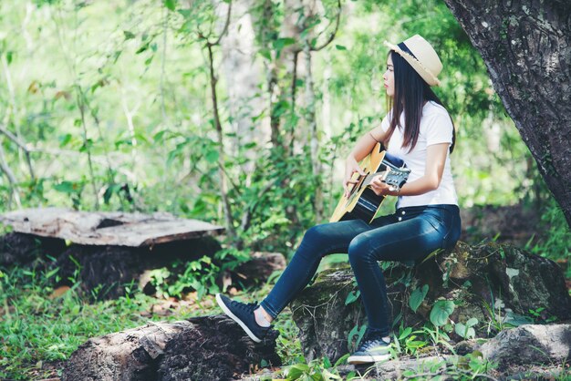 Portrait of beautiful girl playing the guitar with writing at nature