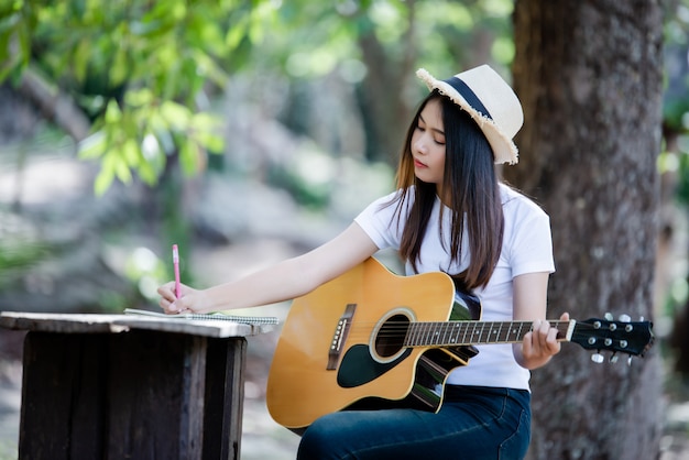 Portrait of beautiful girl playing the guitar with writing at nature