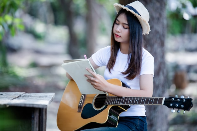 Portrait of beautiful girl playing the guitar with writing at nature