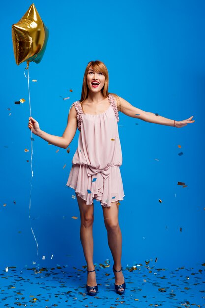 Portrait of beautiful girl resting at party over blue wall