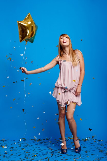 Portrait of beautiful girl resting at party over blue wall